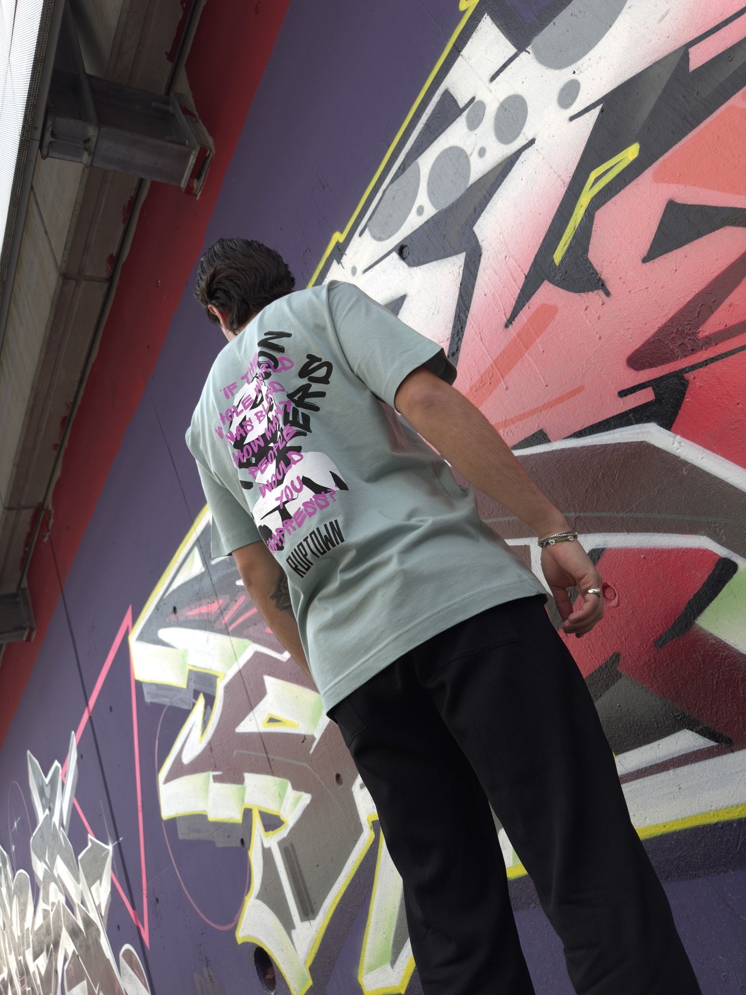 Das hellgrüne Oversized T-Shirt von Ruptown Streetwear vor einem bunten Graffiti